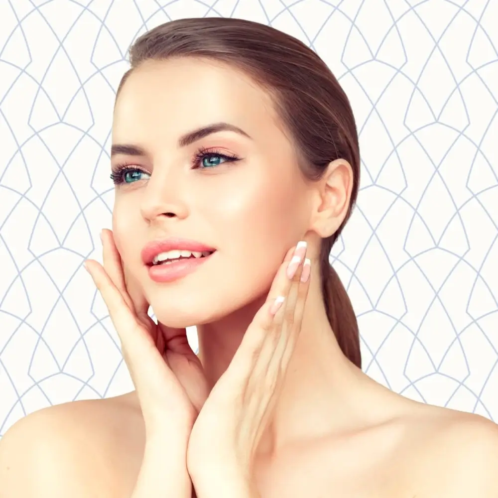 Young woman smiling and posing with both hands on her face | Facials | Andromeda Medspa