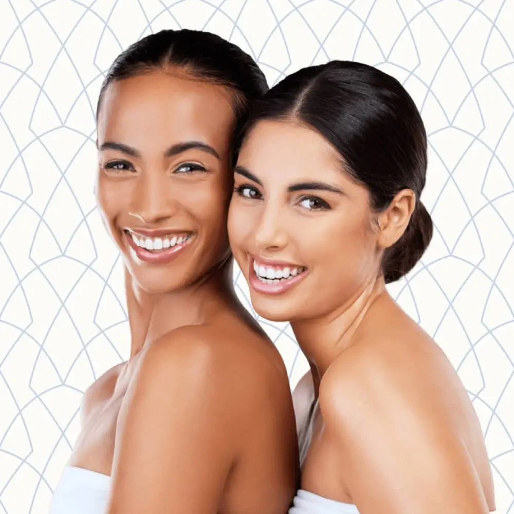 Two young women smiling and posing close to each other | Wellness | Andromeda Medspa